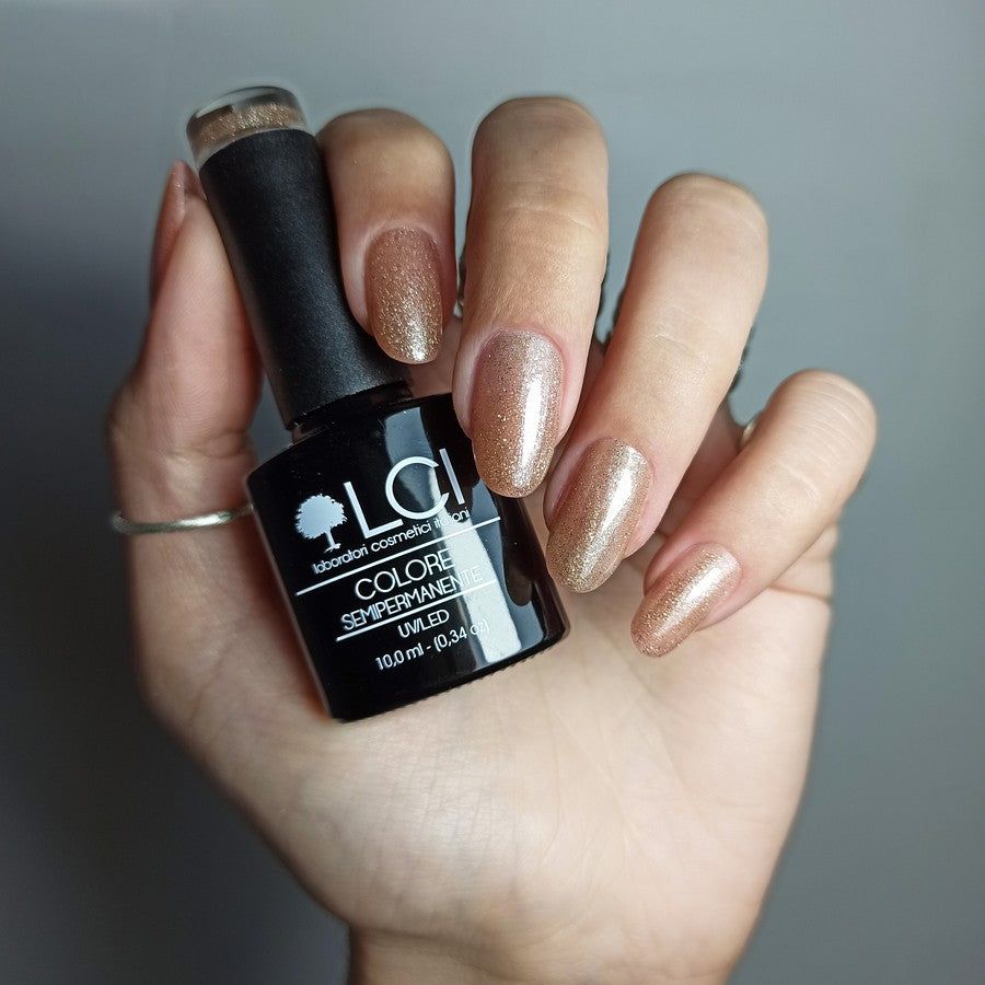Mano con unghie smaltate oro, accanto flacone di smalto. Scritta: LCI, Colore Semipermanente, UVLED.