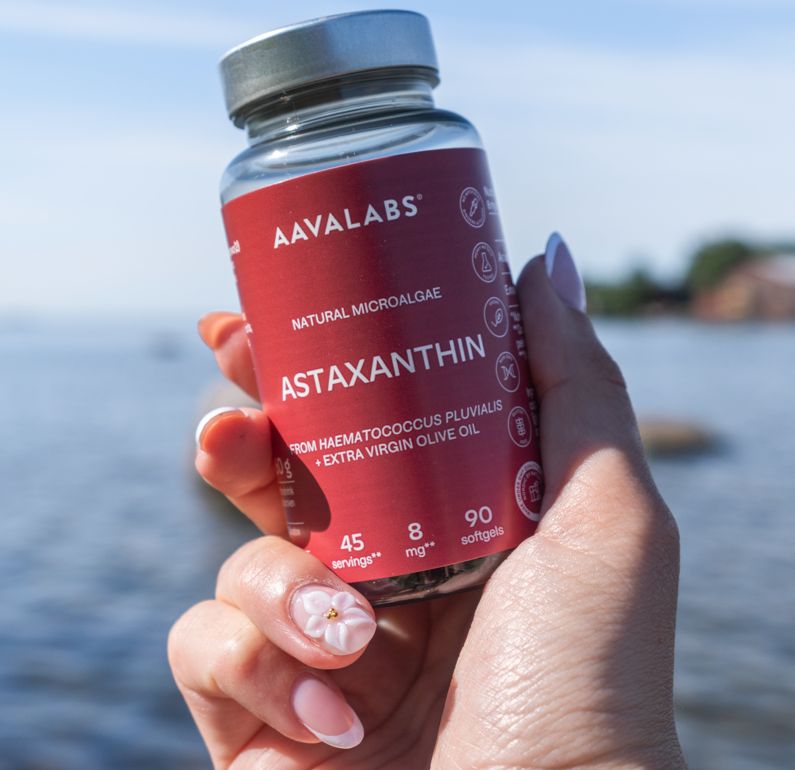 Mano che tiene una bottiglia Aavalabs Astaxantina 8 mg davanti all'acqua.