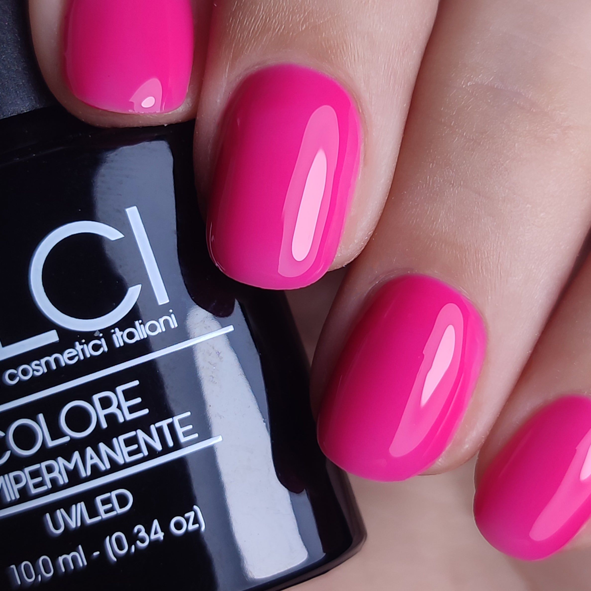 Mano con unghie smaltate rosa fucsia. Flacone smalto con scritta: LCI, Colore Semipermanente, UVLED, 10,0 ml.