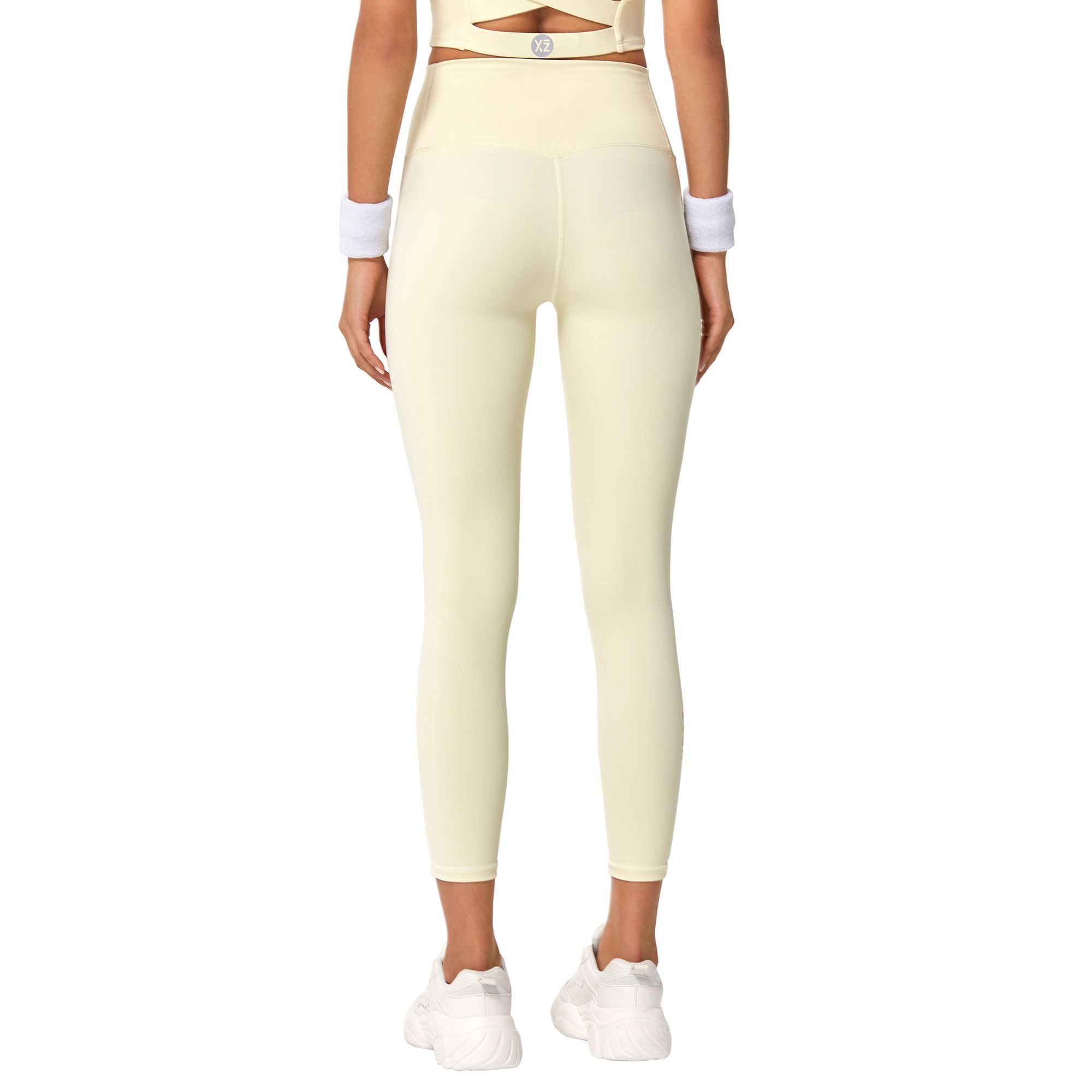 Vista posteriore di un leggings giallo pallido a vita alta con logo bianco in vita e fasce bianche ai polsi.