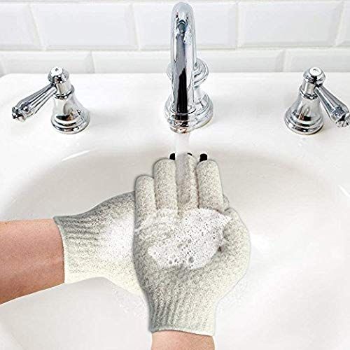 Due guanti da bagno esfolianti grigio chiaro con polsini a coste, appoggiati su un lavandino bianco.