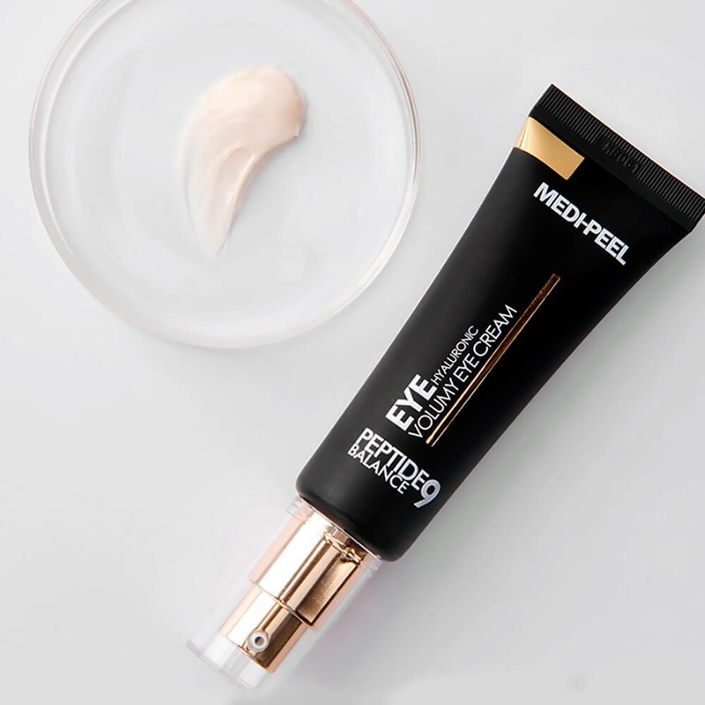 Tubo nero con tappo dorato e un campione di crema accanto. Scritta: MEDI-PEEL PEPTIDE 9 HYALURONIC VOLUMY EYE CREAM.