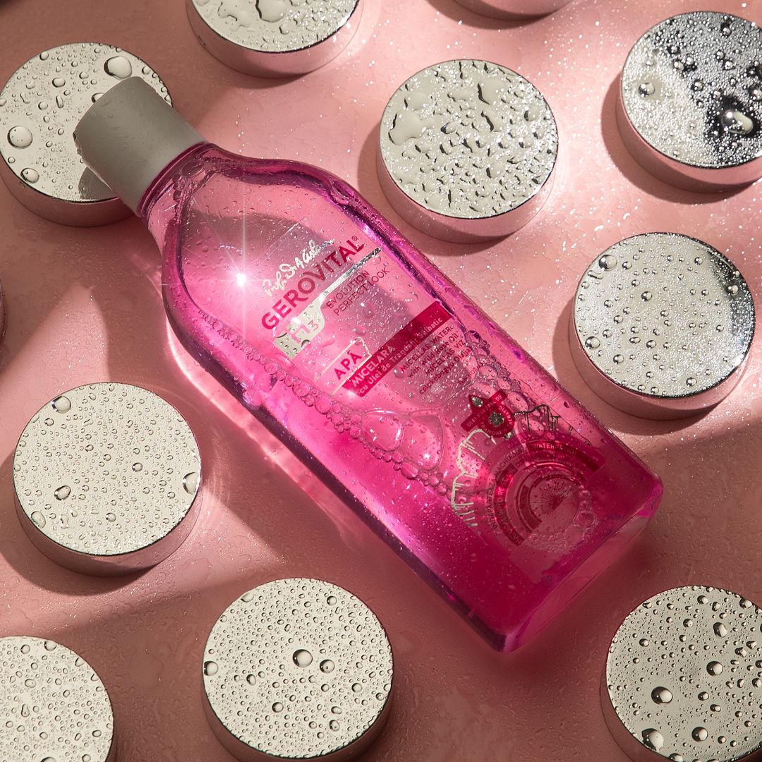 Liquido rosa in bottiglia trasparente con tappo bianco. Etichetta: Gerovital, Acqua Micellare. Sfondo: cerchi argentati.