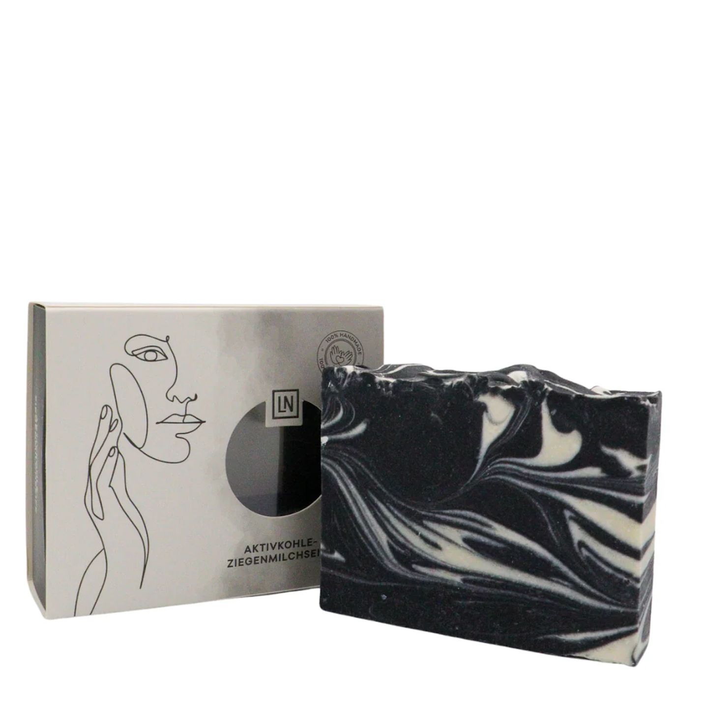 Sapone e scatola. Sapone nero con vortici bianchi. Sulla scatola c'è scritto Aktivkohle-Ziegenmilchseife.