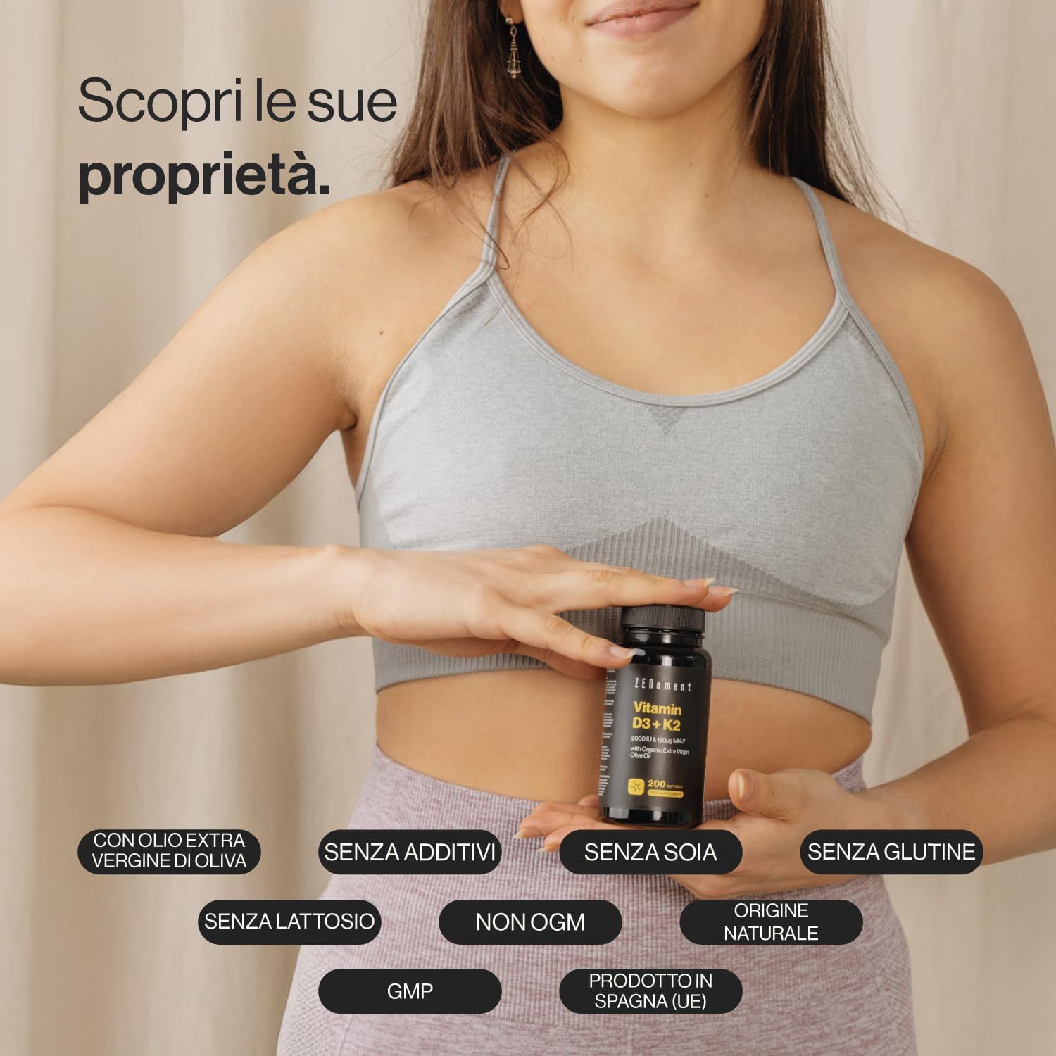 Donna che tiene in mano una bottiglia di capsule di vitamina D3 + K2. Scritta: Zenement. Testo: Senza soia, glutine, lattosio, OGM. Prodotto in Spagna.