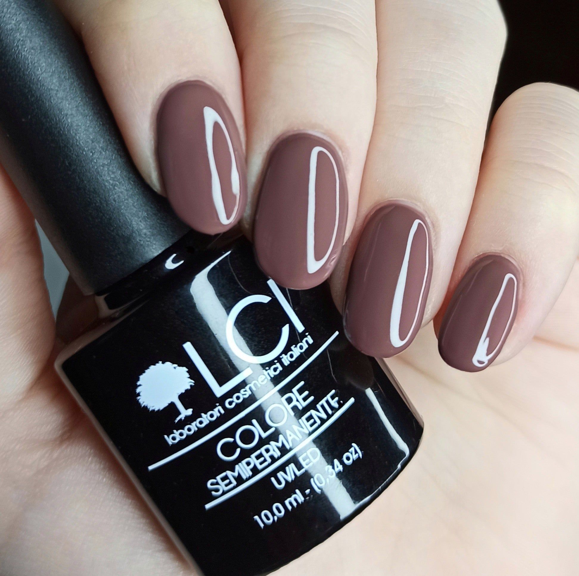 Flacone di smalto e unghie smaltate. Flacone con logo e testo. Unghie smaltate di marrone.