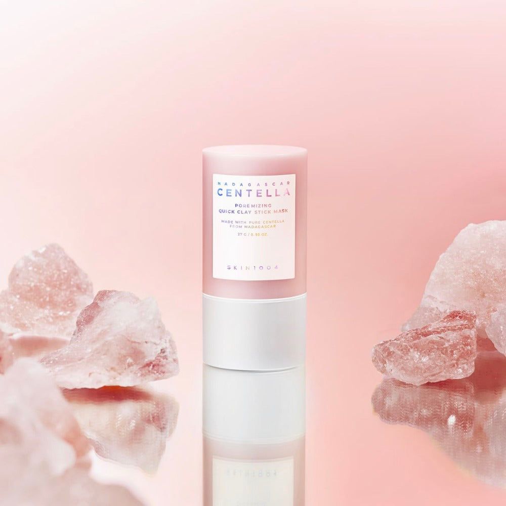 Maschera viso rosa cilindrica, circondata da cristalli rosa. Testo: Madagascar Centella, Poremizing Quick Clay Stick Mask.