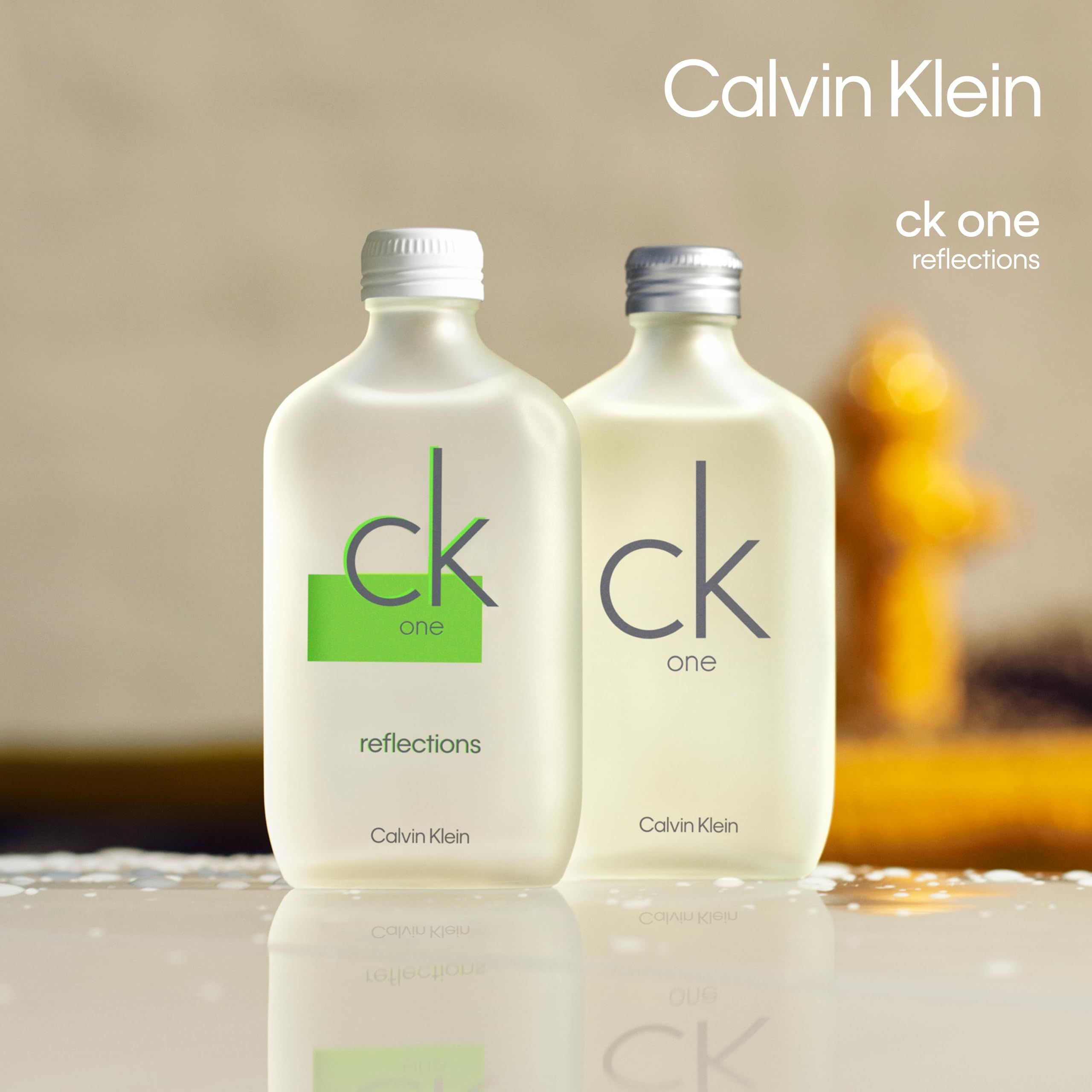 Due flaconi Calvin Klein One Reflections. Flaconi con tappi bianchi e argentati. Sfondo sfocato.