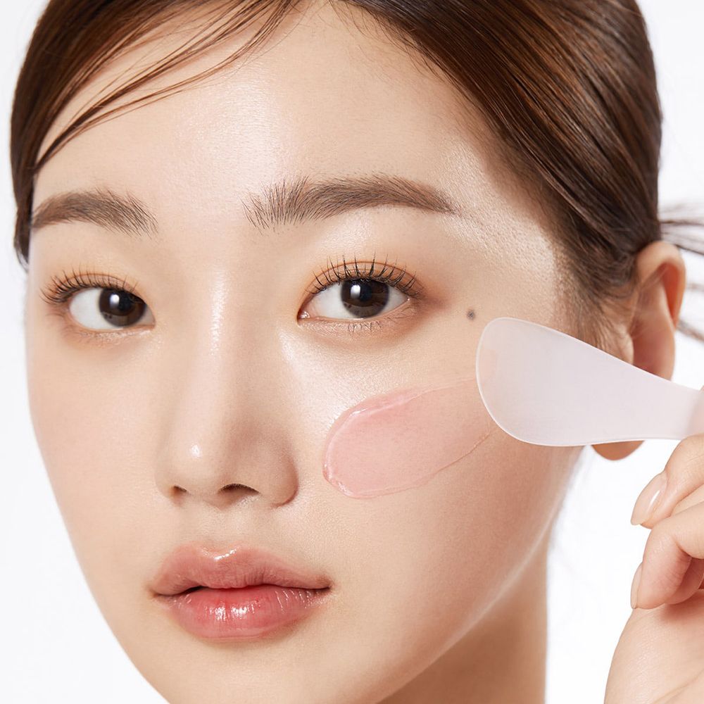 Viso di donna con crema. Sfondo rosa.