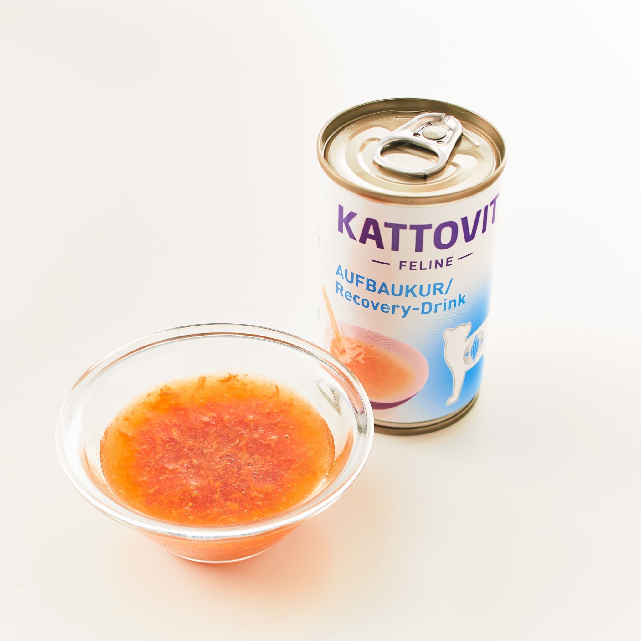 Lattina e ciotola di Kattovit Aufbaukur Drink. Lattina con scritta KATTOVIT, Aufbaukur/Recovery-Drink. Ciotola con liquido.