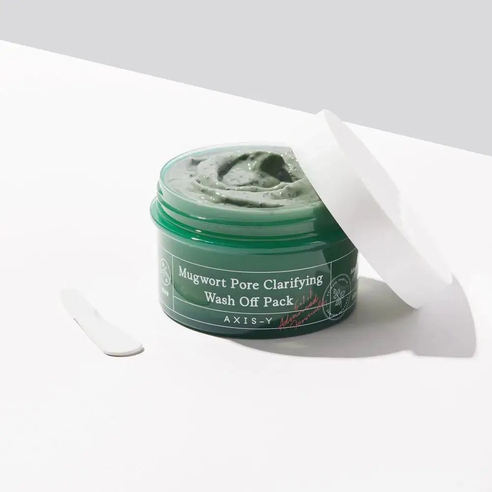 Vasetto verde di maschera per il viso e spatola. Scritta: Mugwort Pore Clarifying Wash Off Pack. Marchio: AXIS-Y.