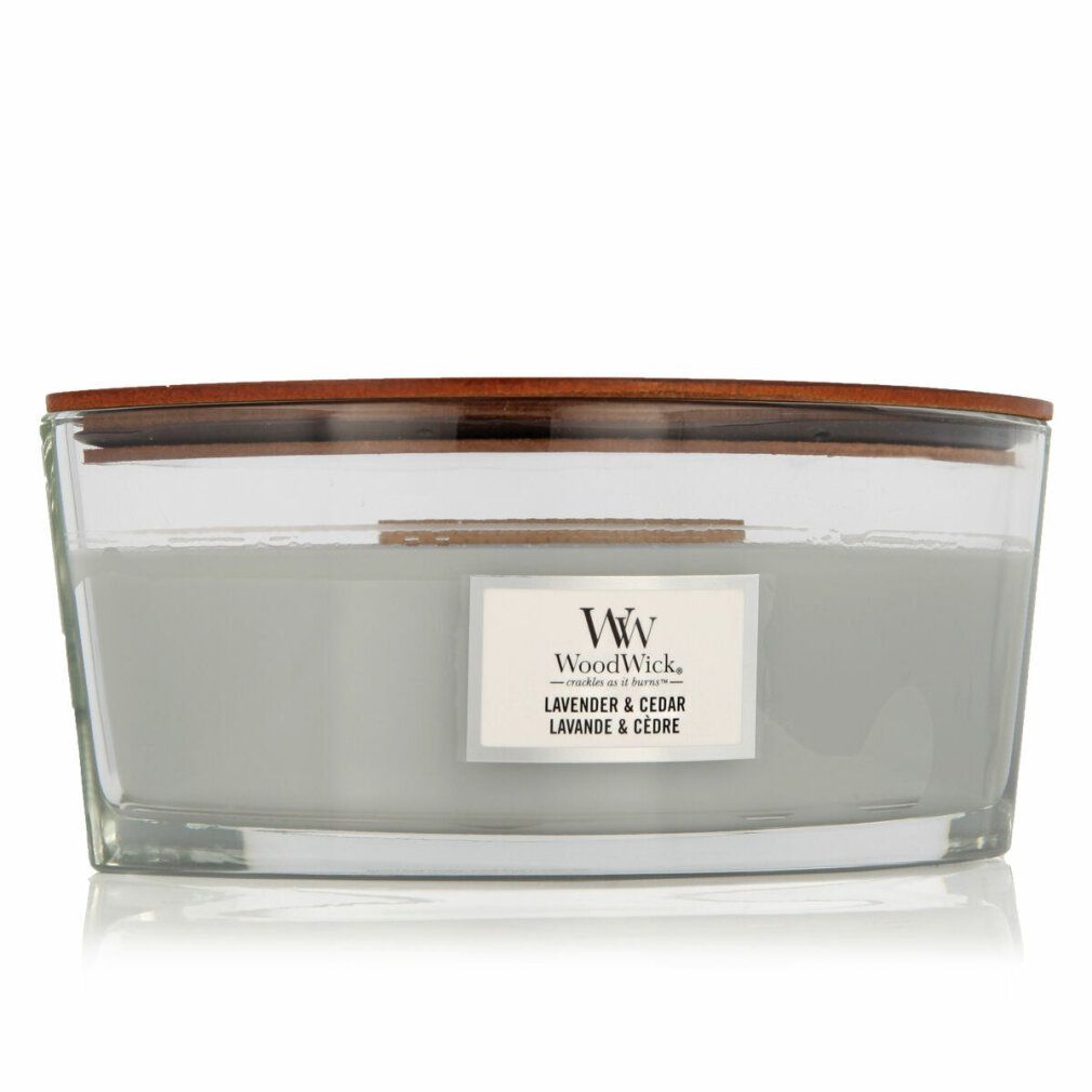 Candela con coperchio in legno. Scritta: WoodWick, Lavanda & Cedro. Contenitore in vetro, cera grigio chiaro.