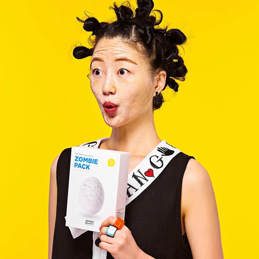 Donna con maschera facciale e capelli raccolti tiene una scatola "Zombie Pack".