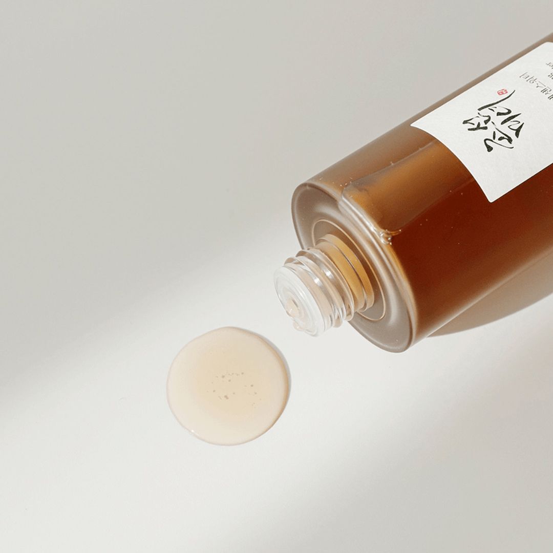 Liquido che gocciola da un flacone su una superficie. Pozzanghera di liquido rotonda. Flacone con etichetta.