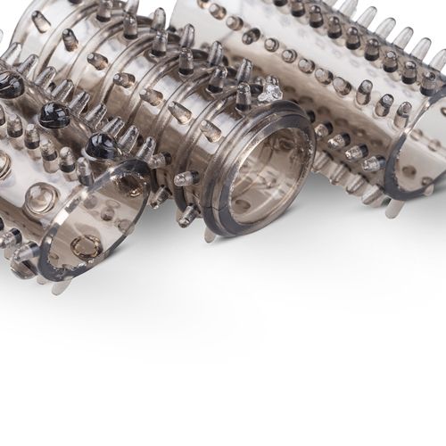 Primo piano di rivestimenti penieni in silicone trasparente con borchie. Su sfondo bianco.