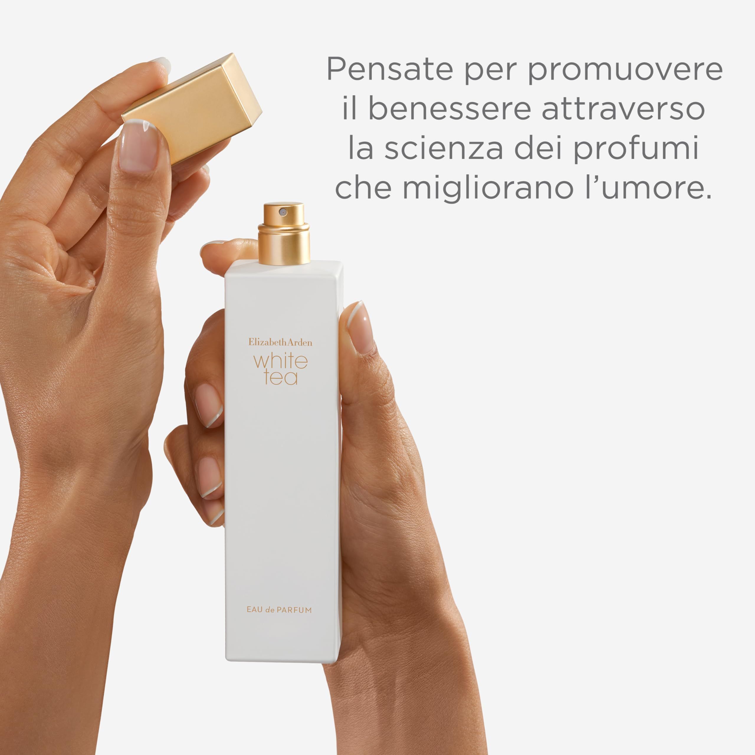 Mani che tengono un flacone di profumo bianco con tappo dorato. Scritta: White Tea. Il tappo viene aperto.