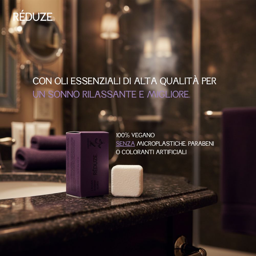 Scatola viola e cubetto doccia bianco su superficie scura. Testo: RÉDUZE.