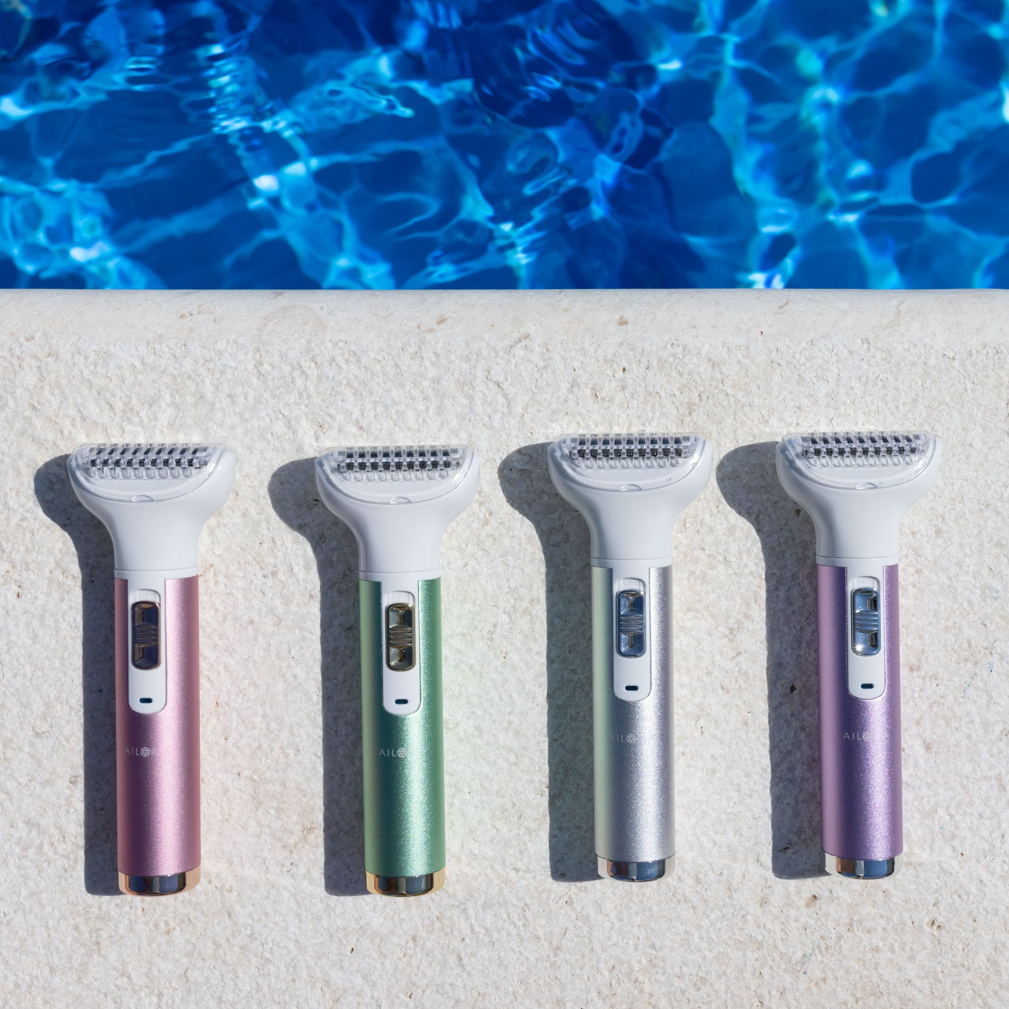 Quattro rasoi di diversi colori: rosa, verde, argento e viola. Tutti hanno una testina bianca.