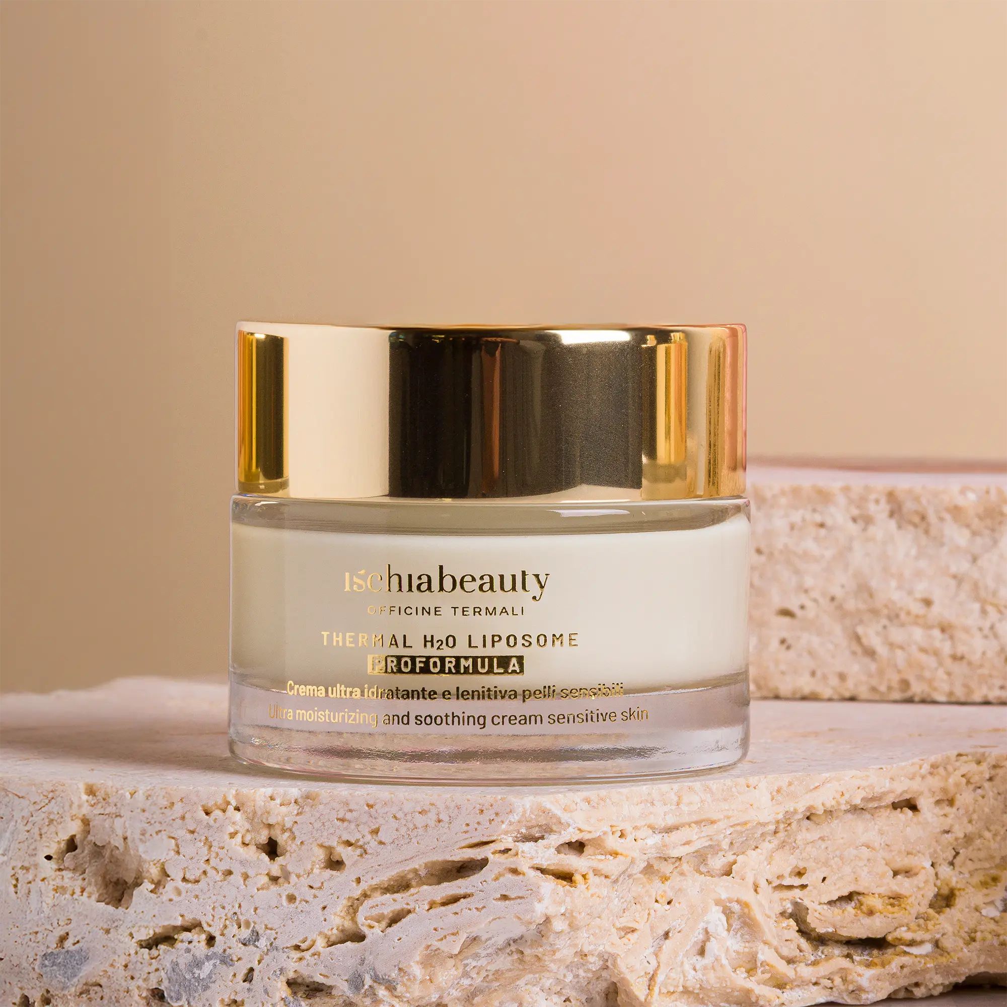 Vaso di crema con coperchio dorato. Testo: ischiabeauty, Thermal H2O Liposome, Proformula. Su pietra.