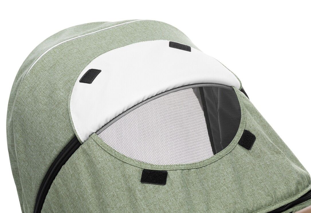 Primo piano della cappottina di un passeggino. Visiera bianca, finestra a rete, tessuto verde.