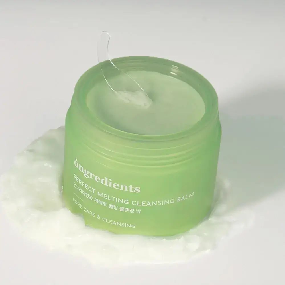 Vasetto verde con balsamo verde. Scritta: Perfect Melting Cleansing Balm. Una spatola trasparente è presente.