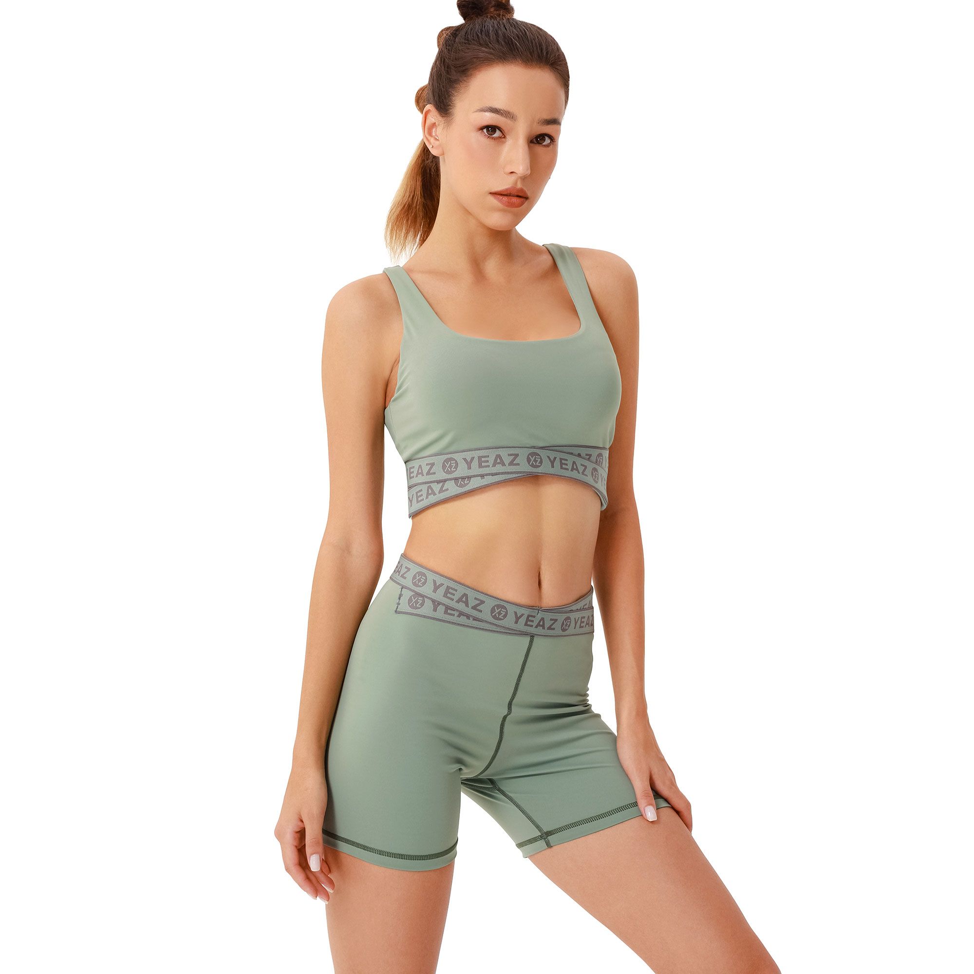 Completo verde con reggiseno sportivo e pantaloncini da ciclista con fascia grigia del marchio.