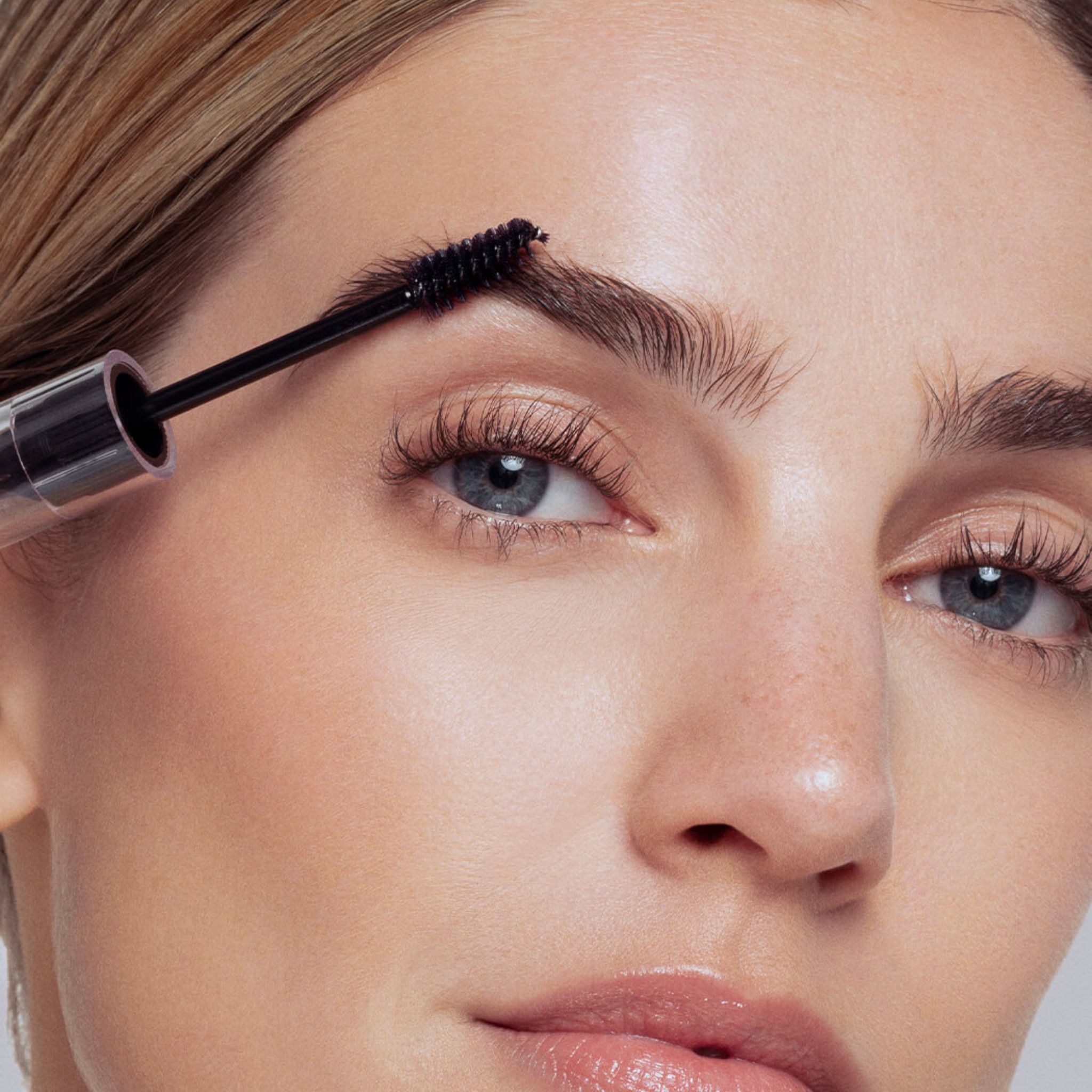 Donna applica gel sopracciglia marrone scuro con applicatore a spazzola.
