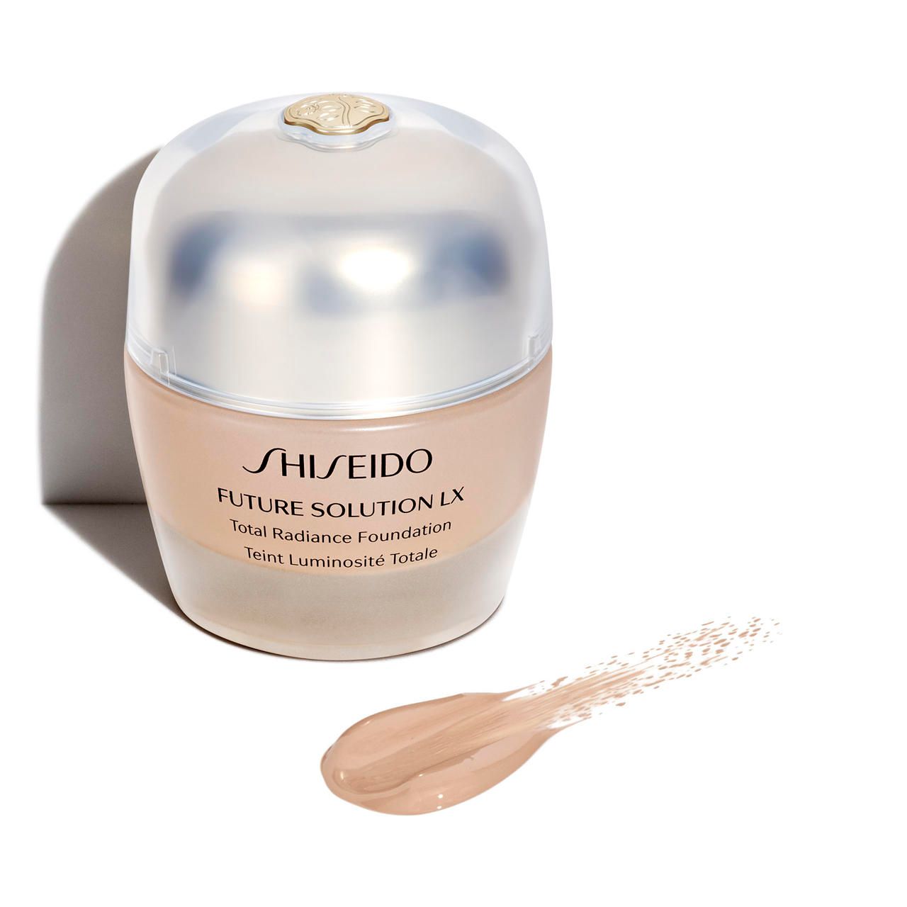 Fondotinta Shiseido Future Solution LX. Flacone beige con coperchio. Macchia di colore accanto. Scritta e nome.