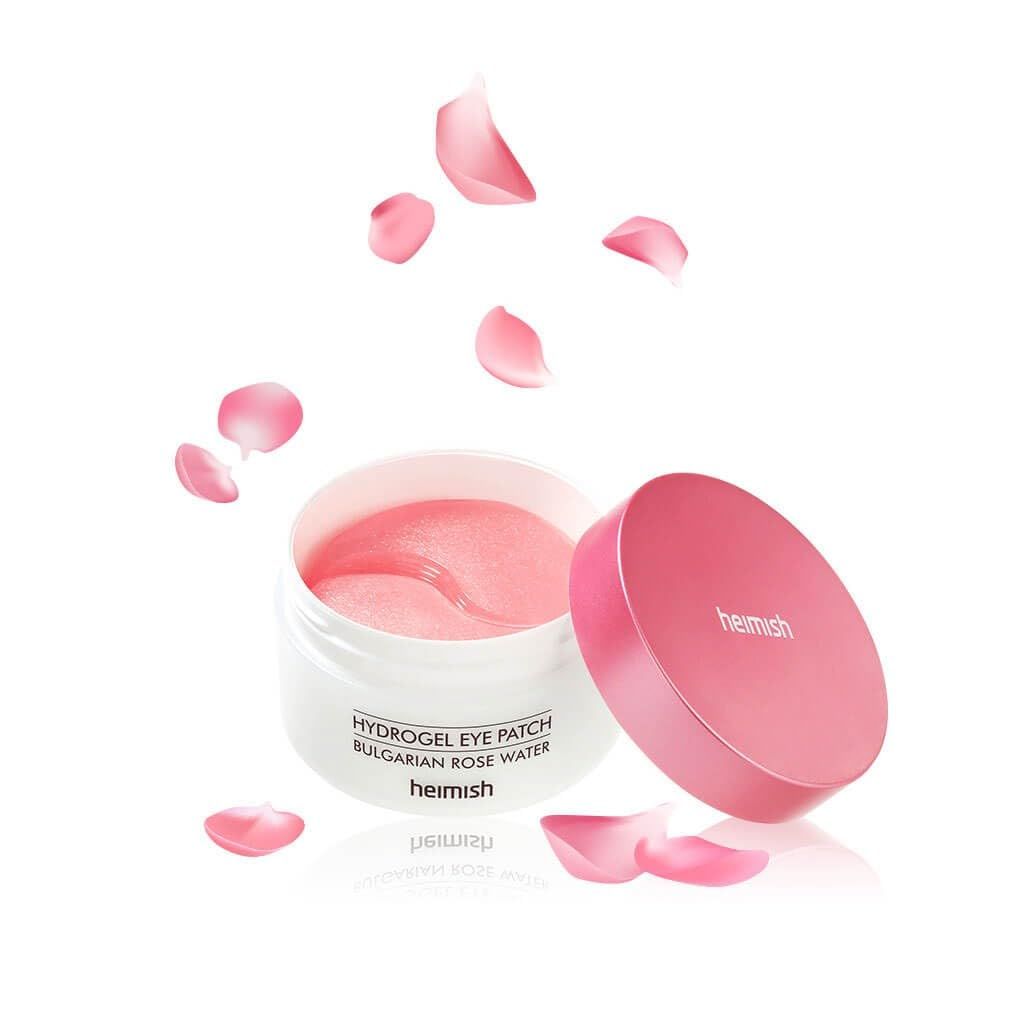 Vasetto bianco con coperchio rosa e patch occhi. Petali rosa circondano il prodotto. Scritta: Heimish, Hydrogel Eye Patch Bulgarian Rose Water.