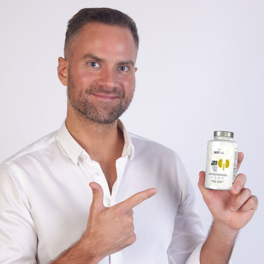 Uomo tiene in mano un flacone bianco "BEST LAB URO BEST". Indica il flacone con il dito.
