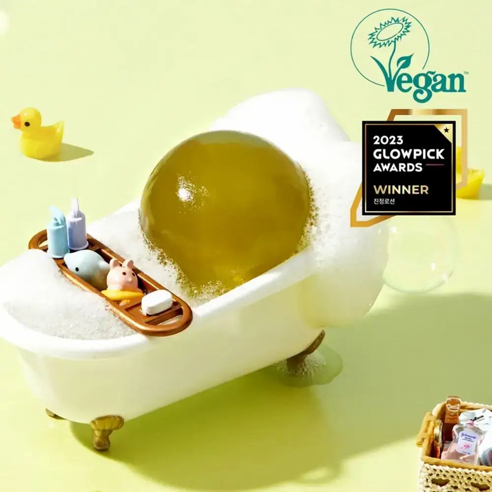 Oggetto sferico verde in una vasca da bagno con schiuma. Logo vegano e premio.