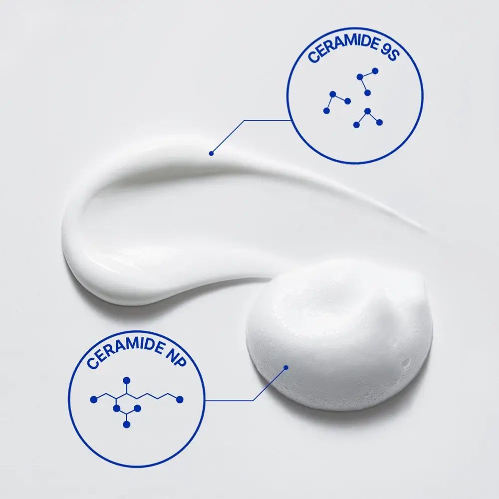 Primo piano di schiuma bianca. Due cerchi mostrano le strutture chimiche di Ceramide 9S e Ceramide NP.