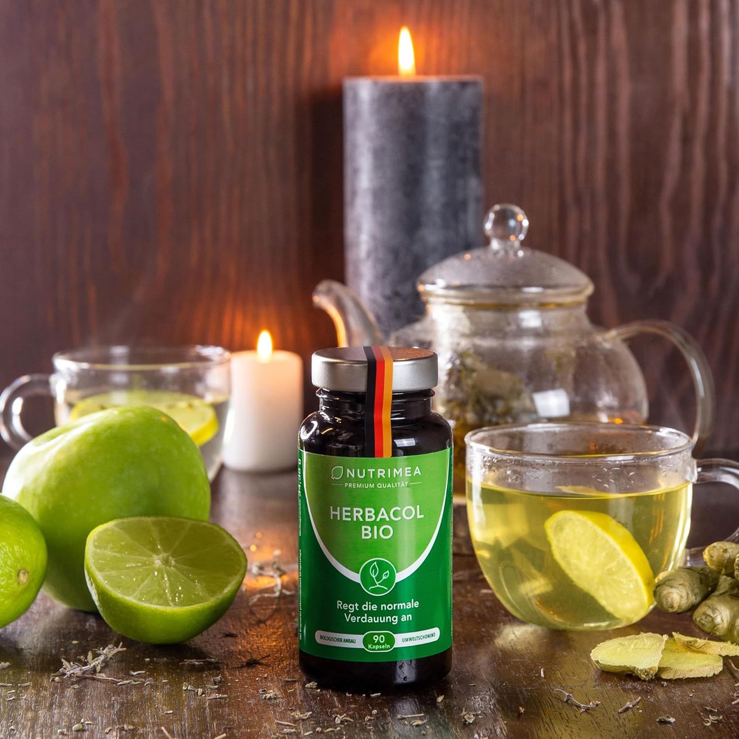 Bottiglia HERBACOL BIO accanto a mele verdi, tè e candele. Prodotto nel contesto. 90 capsule. Stimola la normale digestione.