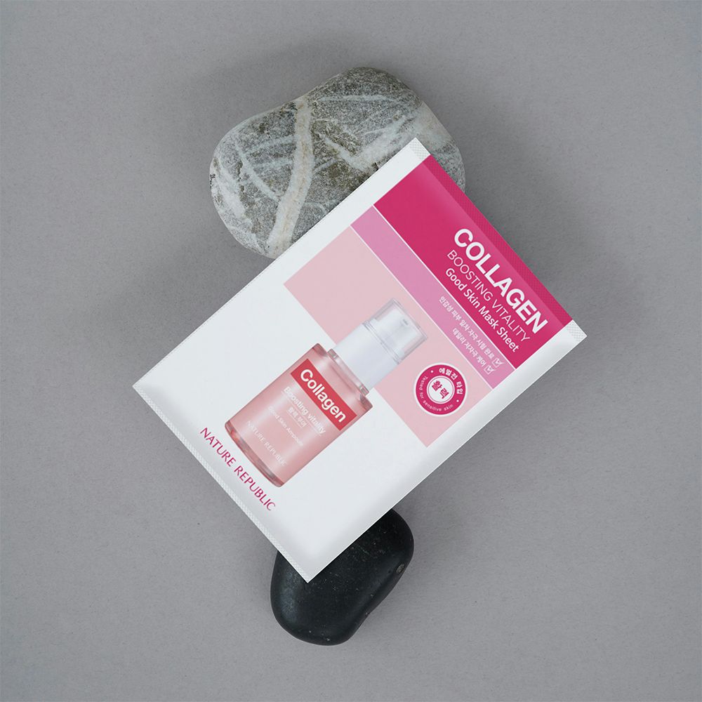 Confezione bianca con dettagli rosa. Scritta: Collagen, Good Skin Mask Sheet. Immagine del prodotto sottostante. Pietre sullo sfondo.
