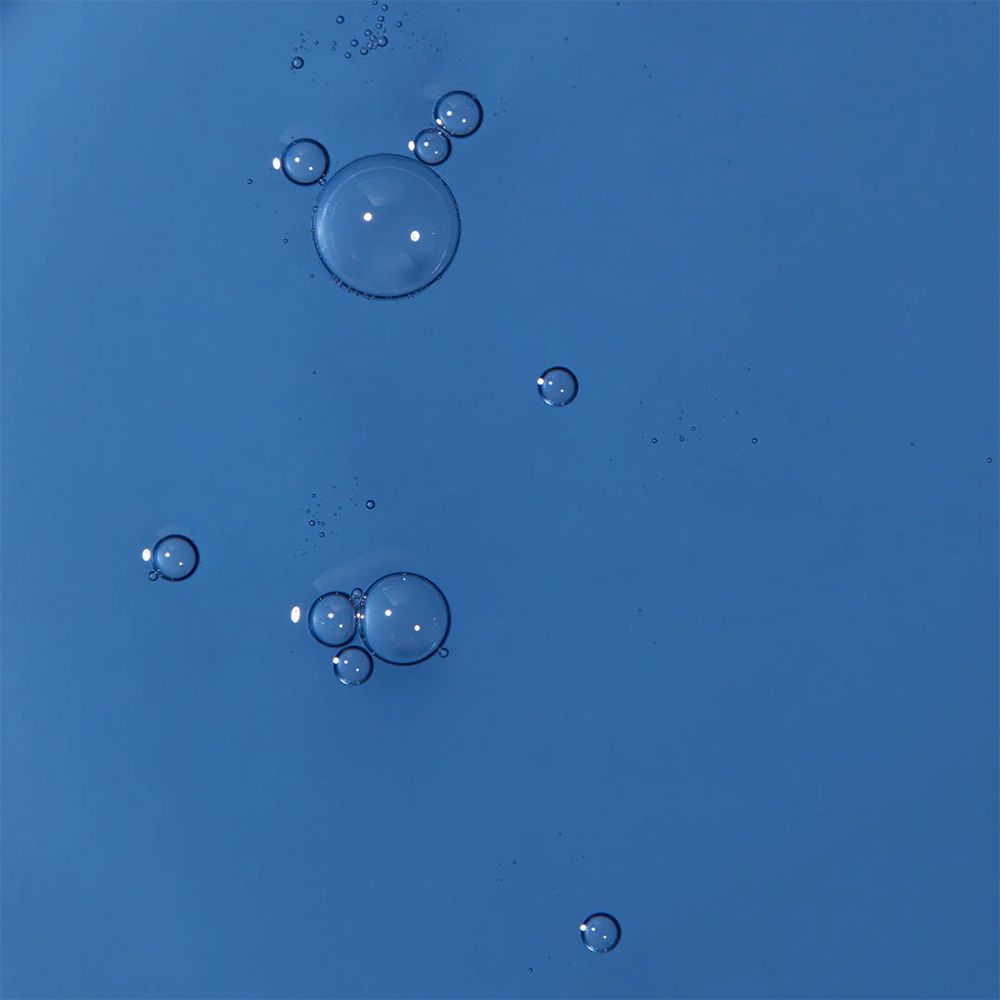 Primo piano di bolle di siero blu su sfondo blu.