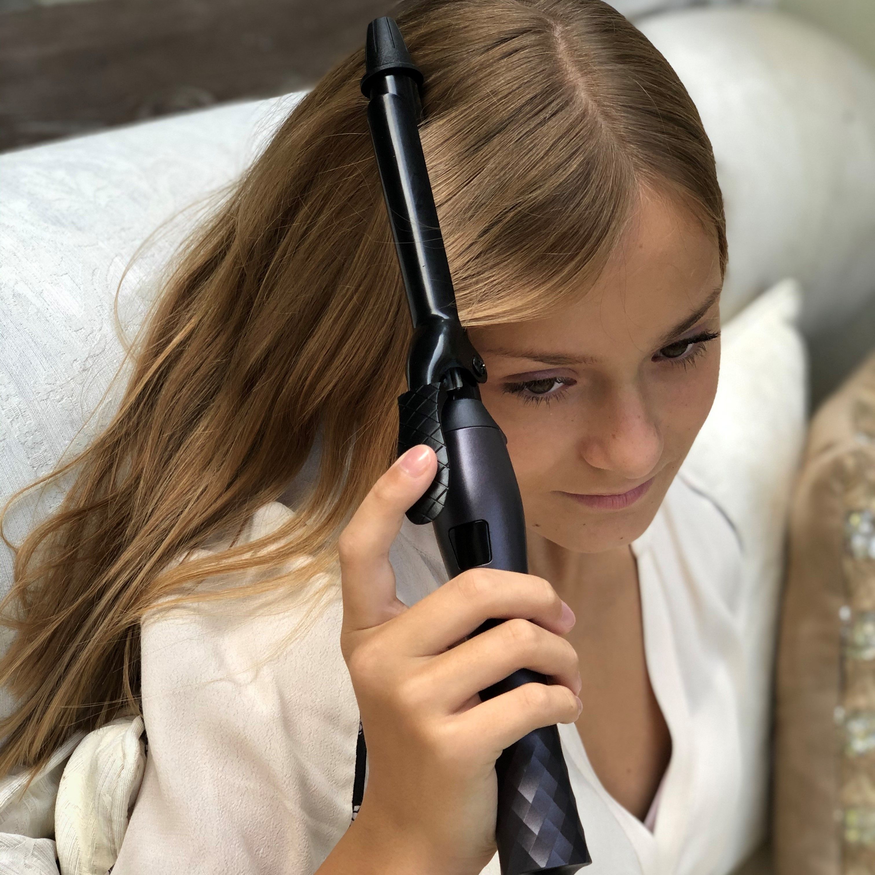 Ragazza tiene un arricciacapelli nero. Logo AILORIA visibile. Arricciacapelli in ceramica.