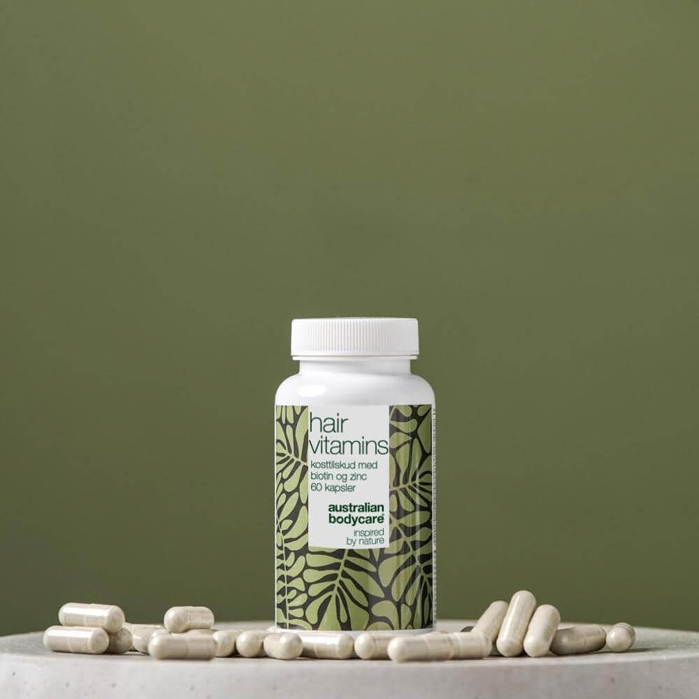 Flacone bianco con capsule. Scritta: Hair Vitamins. Marchio: Australian Bodycare. Capsule accanto.