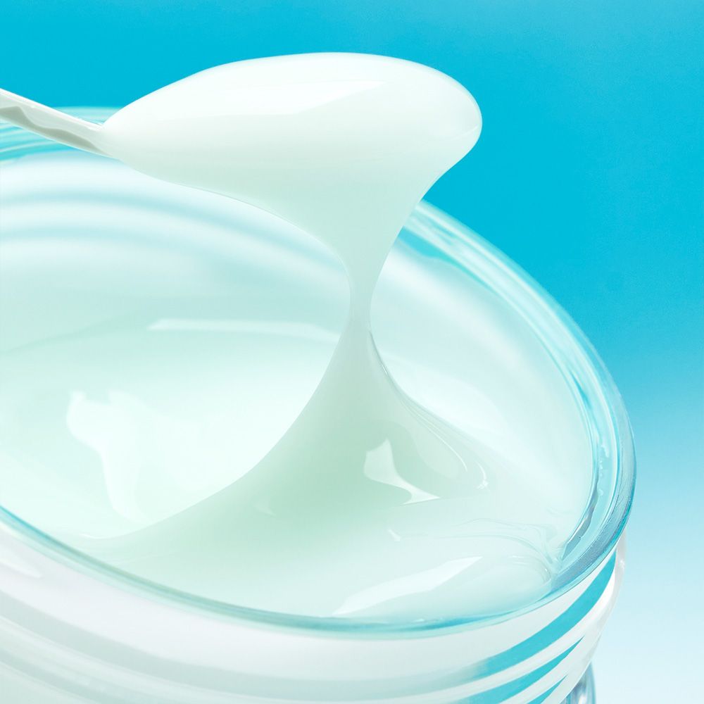 Una spatola preleva la crema Numbuzin Pantothenic B5 da un contenitore di vetro.