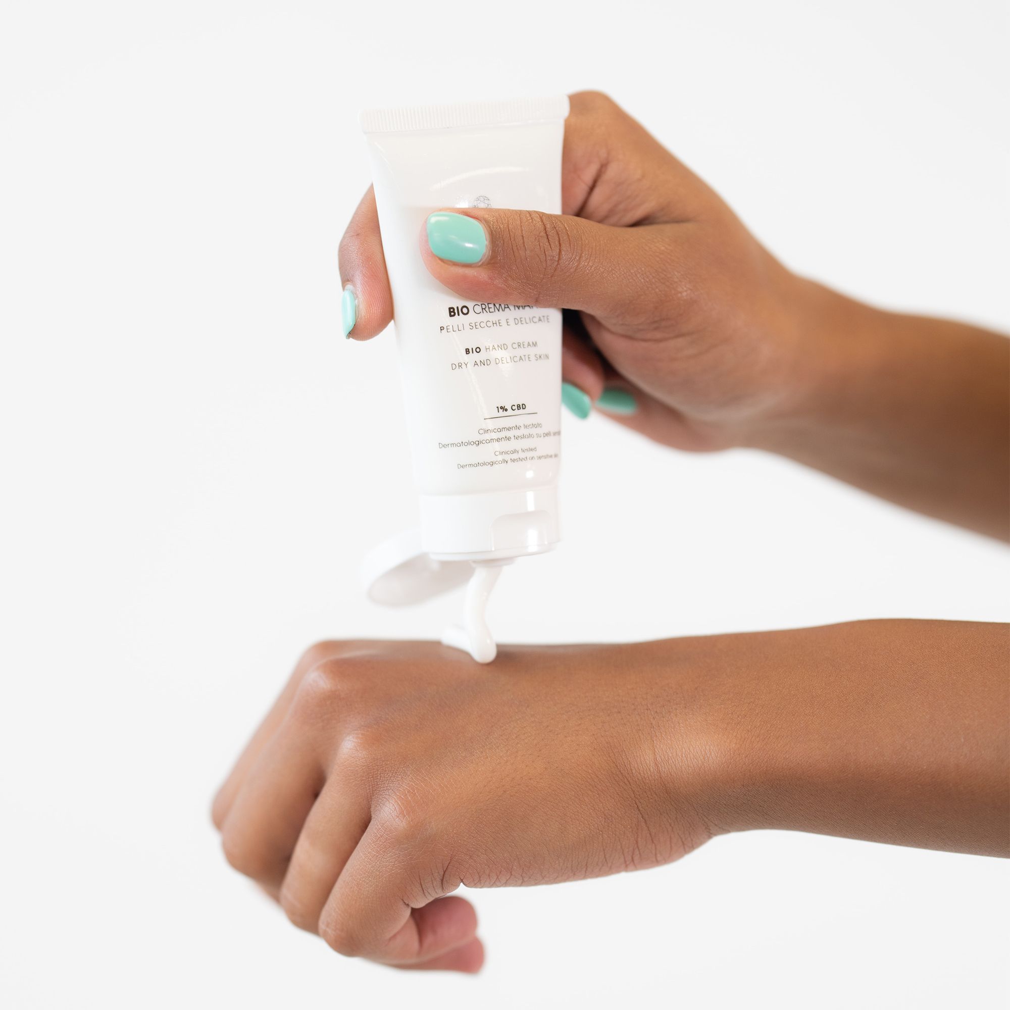 Tubo bianco tenuto in mano. Prodotto applicato sulla mano. Testo: BIO CREMA MANI, 1% CBD. Marchio: PLANTADEA.