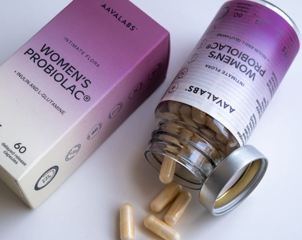 Flacone Aavalabs Women's Probiolac aperto, capsule sparse, accanto alla confezione.