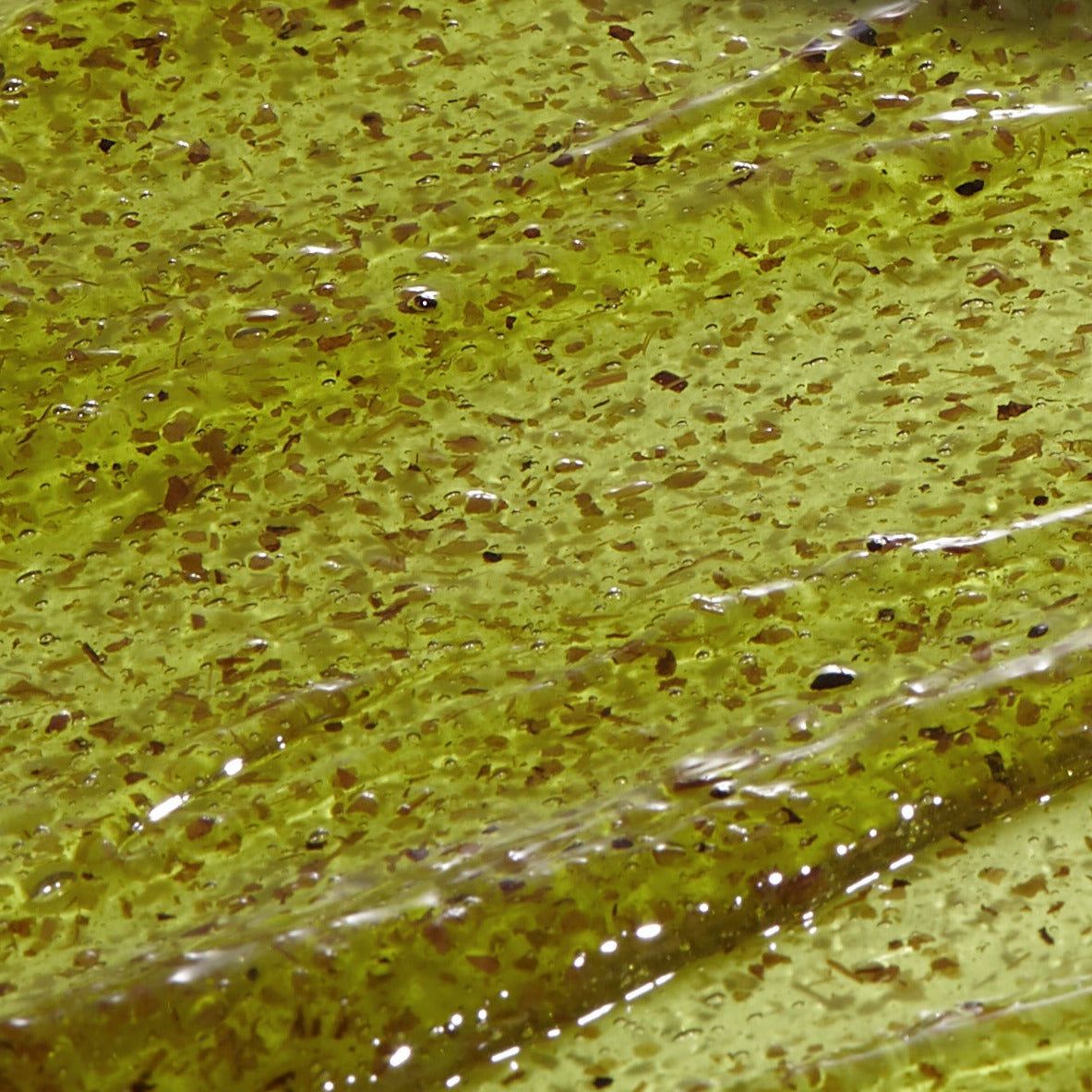 Primo piano di una sostanza gelatinosa gialla con piccole particelle. Superficie strutturata.