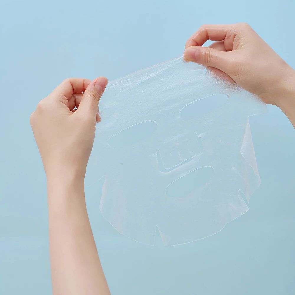 Mani che tengono una maschera idratante trasparente con ritagli per occhi e bocca.