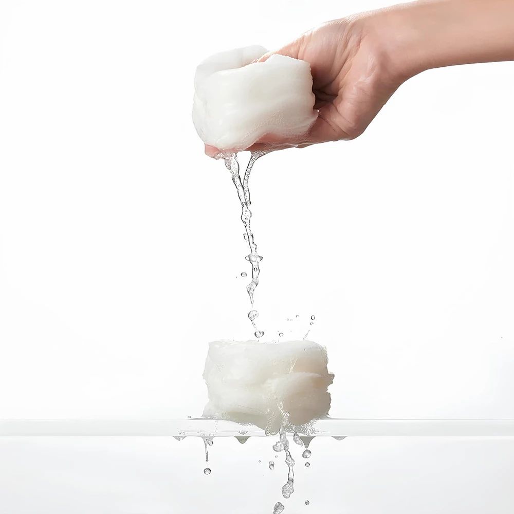 Due pad bianchi bagnati. Uno tenuto da una mano, l'acqua gocciola sull'altro.