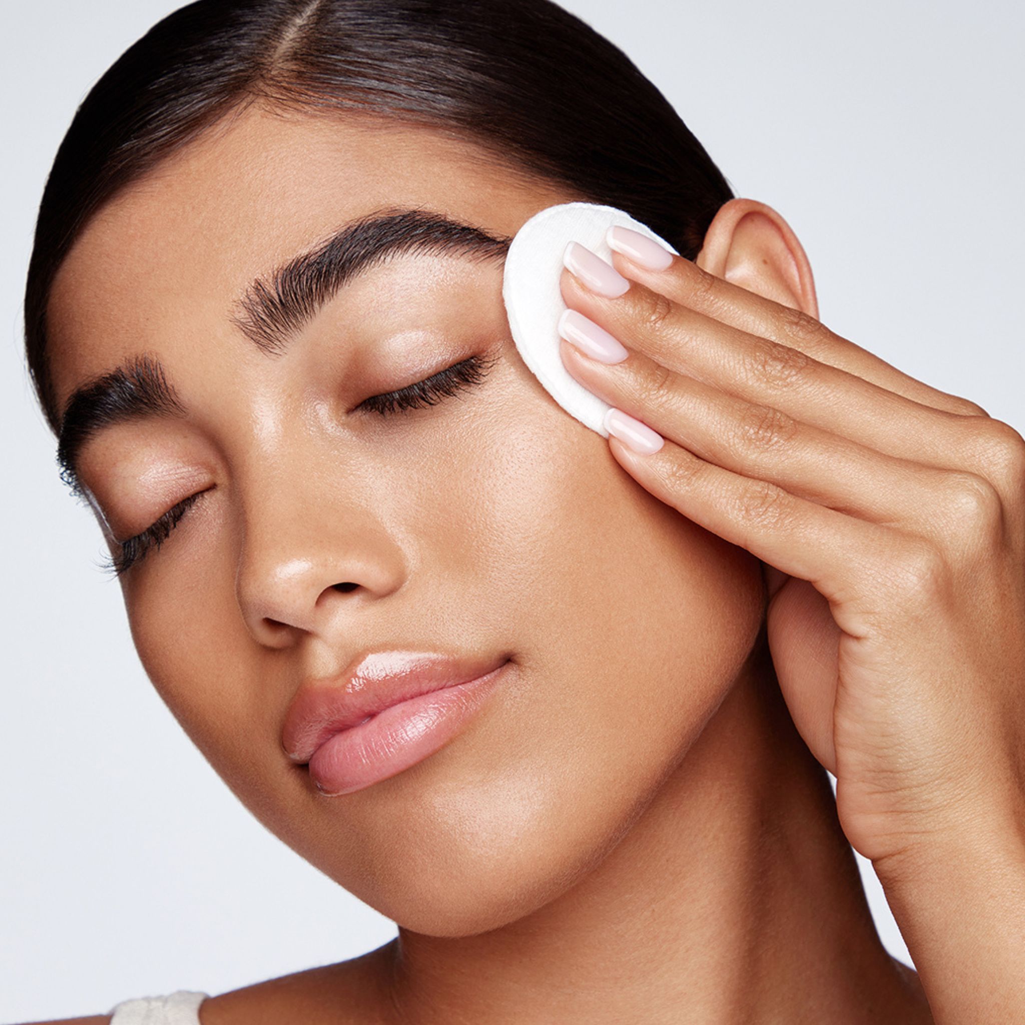 Primo piano di una persona che usa un batuffolo di cotone sull'occhio. Contesto di cura della pelle.