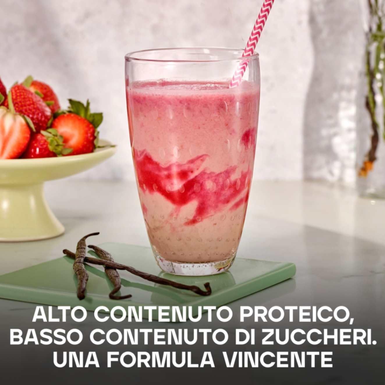 Bicchiere con bevanda rosa, fragole, baccelli di vaniglia. Testo: ALTO CONTENUTO PROTEICO, BASSO ZUCCHERI.