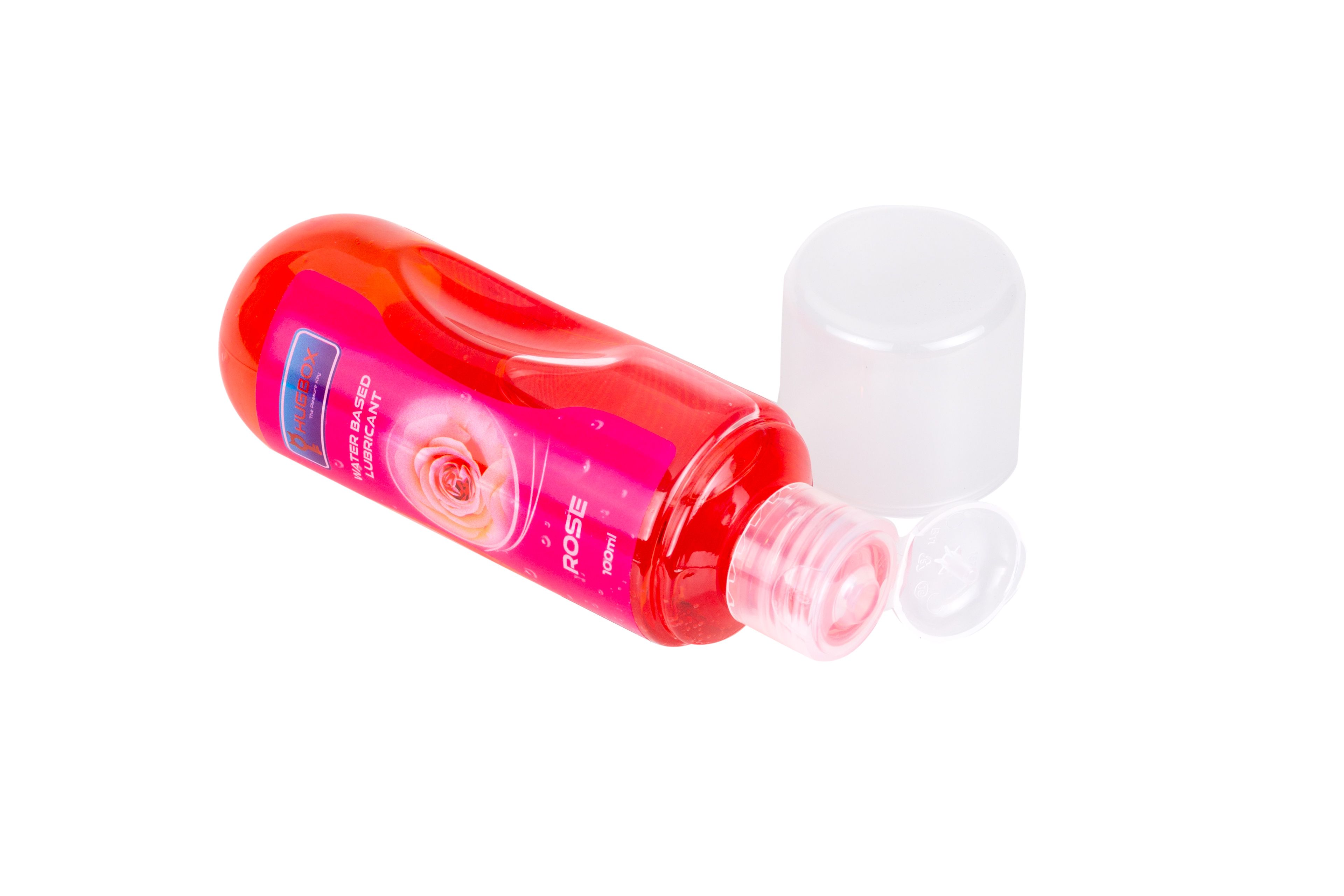 Flacone rosso, liquido rosa, sdraiato. Tappo accanto. Etichetta con testo e rosa. Nome prodotto non visibile.