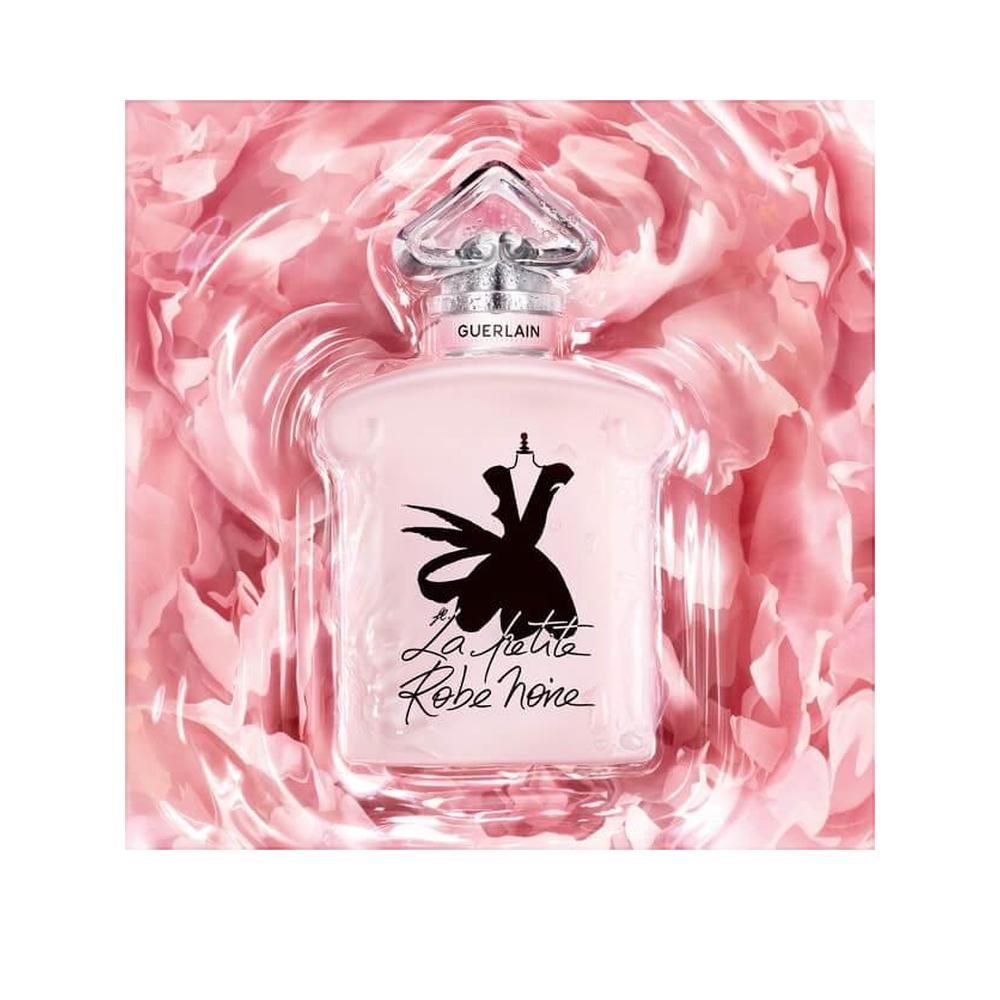 Flacone rosa in confezione con petali di rosa. Tappo argento, scritta Guerlain. La Petite Robe Noire.