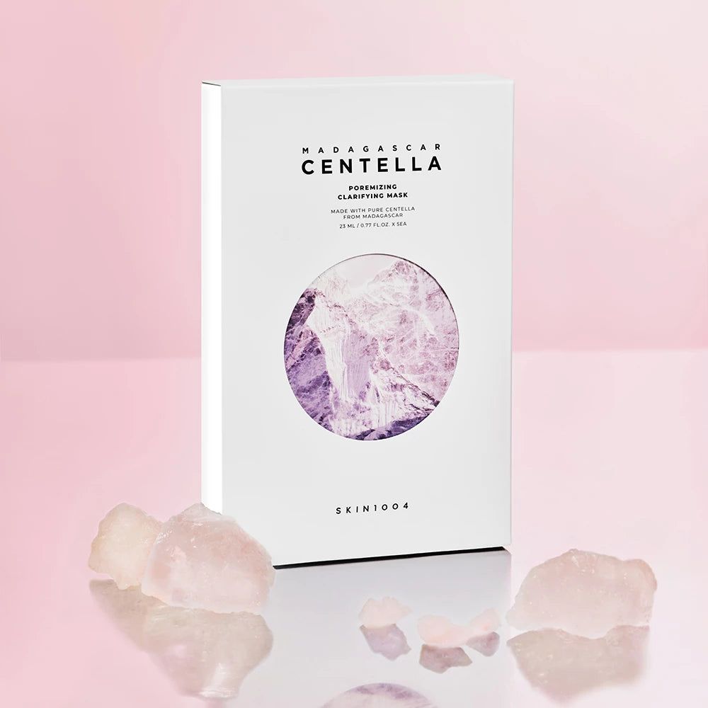 Scatola bianca con maschera viso. Testo: MADAGASCAR CENTELLA, Poremizing Clarifying Mask. Cristalli rosa davanti.