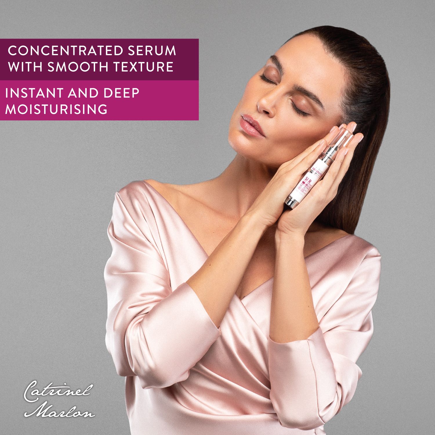 Donna tiene in mano un flacone di Gerovital Siero Concentrato. Tocca la sua pelle con la punta. Sfondo grigio.