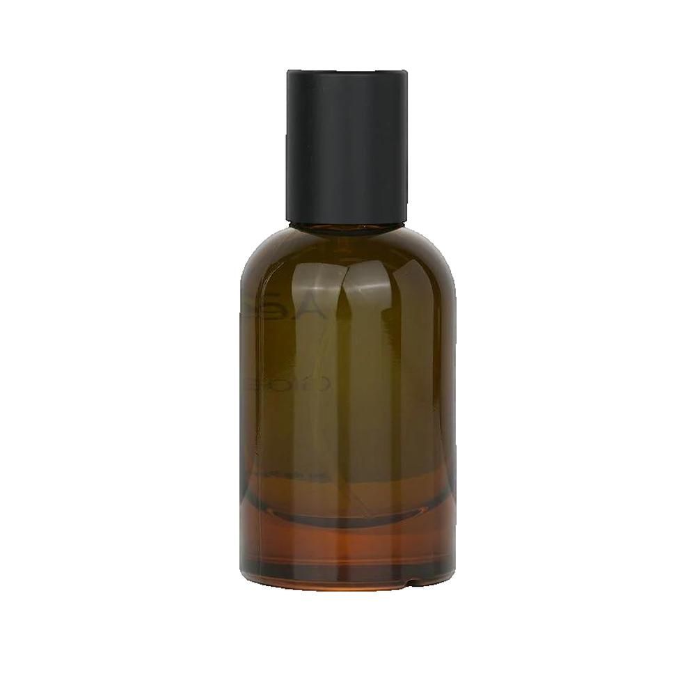 Flacone in vetro marrone con tappo nero. Logo Clarins sull'etichetta. Profumo.